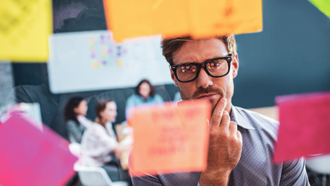 A business manager looking at sticky notes on a window