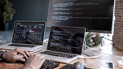 Man working on two laptops and desktop monitor