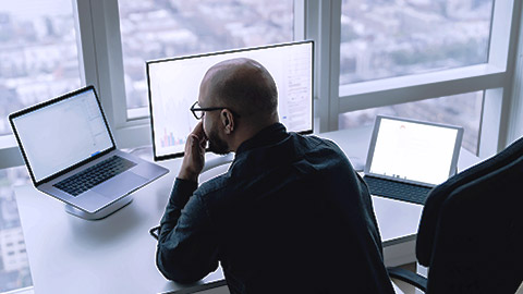 Backview of a man seriously analyzing data on computer