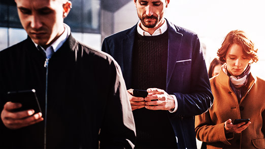 a group of people using celphone while walking on the street