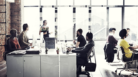 a group of employees in the office listening to a manager about policies and procedures