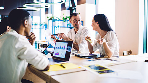 A small, professional team holding a casual meeting in a common area in their modern office