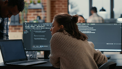 Software programer putting laptop with source code on colleague coder desk asking for opinion about database