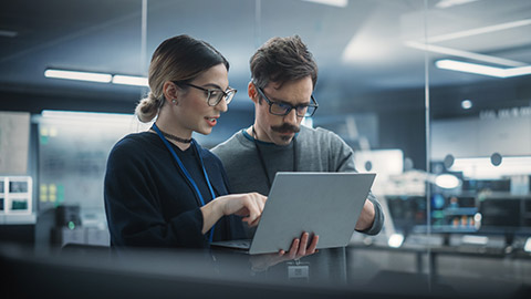 Portrait of Two Creative Young Female and Male Engineers Using Laptop Computer to Analyze and Discuss