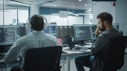 Office: Professional Black IT Programmer Uses Headphones while Working on Desktop Computer