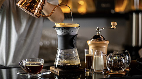 Barista making drip coffee by pouring spills hot water on coffee ground