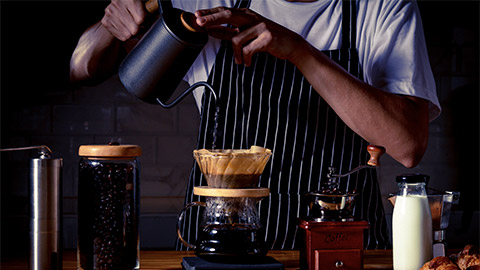 Coffee shop concept : Professional barista preparing coffee using chemex pour over coffee maker and drip kettle.