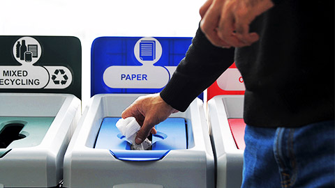 A person throwing garbage in segrated bins.