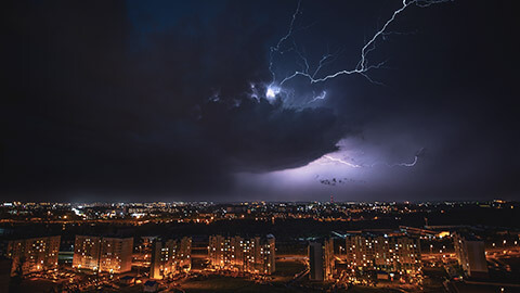 A wide night shot of a large storm over a city