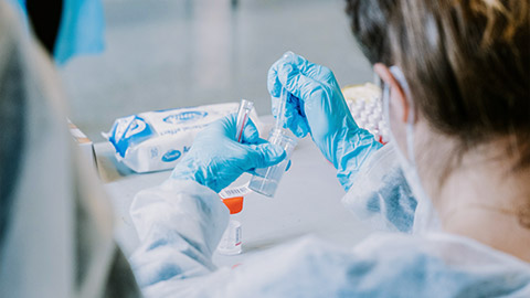 A close view of a clinic worker testing samples while wearing PPE