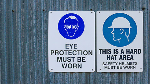 A pair of safety signs on the wall of a construction site