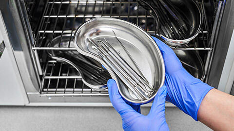 A worker placing vet tools into a steriliser