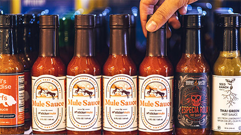 A range of hot sauces on a supermarket shelf, with tamper evident seals