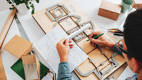 A designer working with a diecut outline on a desk