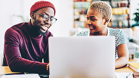 2 young designers discussing a project while looking at a laptop