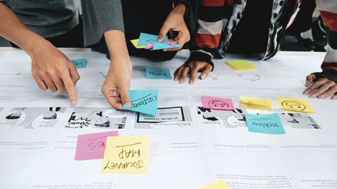 A group of UX designers standing around a table discussing a project