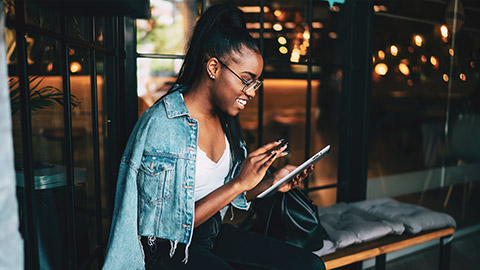 A young designer sitting in an outdoor environment interacting with an app on a tablet device