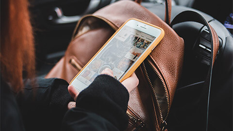 A close shot of a person interacting with their smart device, while seated in a car