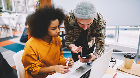 2 designers testing websites on a laptop and phone