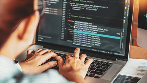 Over the shoulder shot of a programmer writing code on a laptop