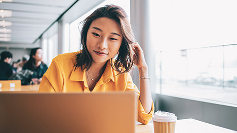 A young designer working on a laptop in an open office environment