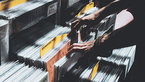 A cloase view of a person looking for a vinyl record in a shot