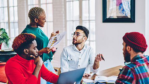 A group of marketing professionals sitting at a table talking about a project