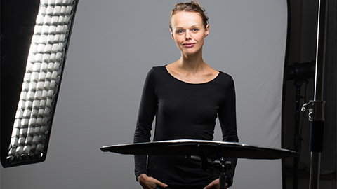 A model posing in a studio with lights and a reflector