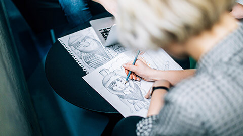 Over-the-shoulder shot of an illustrator working on a pencil drawing