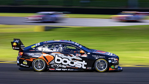 A V8 supercar driving at high speed, shot with a slow shutter speed