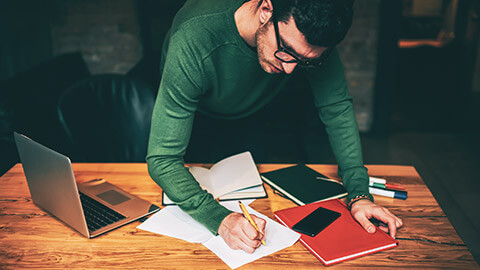 A designer standing at a desk writing notes to be added to brand guidelines