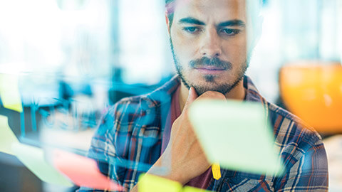 A designer checking project sticky notes on a glass window