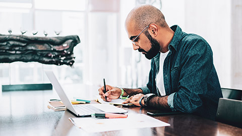 A designer sitting at a desk working on a research brief