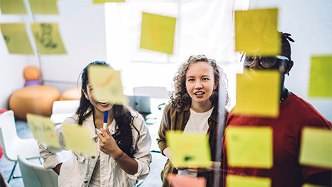 A small team affinity diagramming a concept with sticky notes