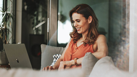 A business owner sitting on a couch working on their website on a laptop