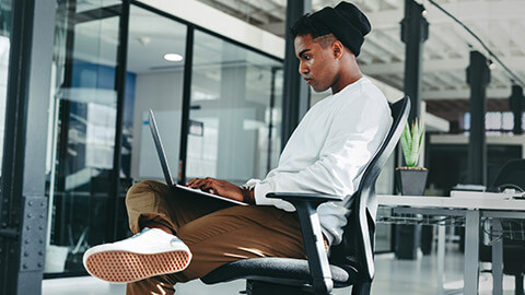 A designer sitting in an office working on a site on a laptop