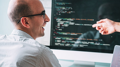 A designer talking to a colleague while working on a coding task