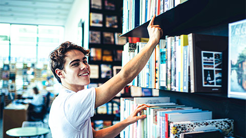 A developer taking a software book off of a library shelf, so that they can reference it while working