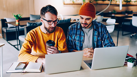 2 developers discussing a project on a laptop