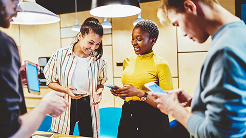 A group of designers standing around a table looking at app prototypes on phones