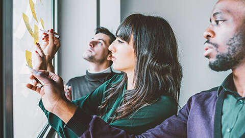 A group of designers working on the UX process using sticky notes on a window