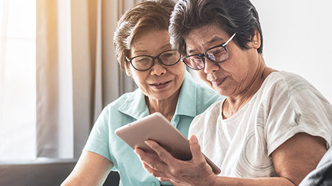 2 elderly Asian ladies using a tablet device