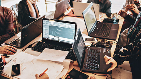 A group of employees with Windows laptops at a communal work table