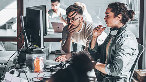 Programmers working on a problem on a desktop computer system