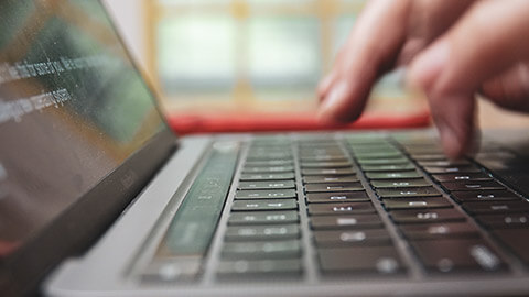 A close view of a person typing on the keyboard of a laptop