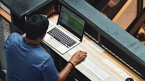 Over-the-shoulder view of a person using a database program on a laptop