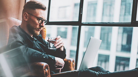 A hipster dude writing a blog on his laptop