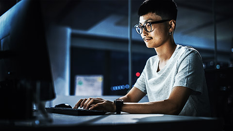 A programmer with glasses working in a desktop screen.