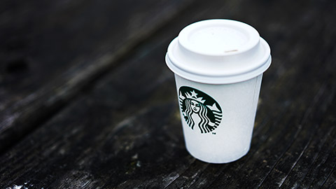 A paper cup on a wooden bench or table