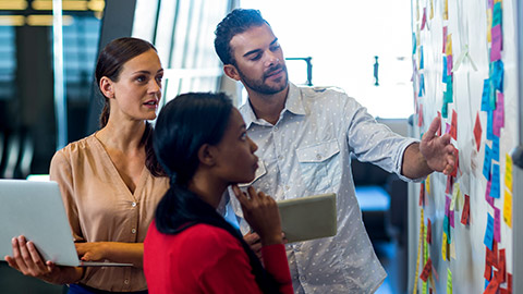 A work group discussing planning with sticky notes on a wall